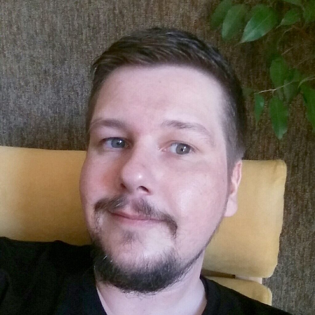 Foto von Björn: Mann mit kurzem dunkelblonden Haar und einem kurzen Vollbart auf einem gelben Sessel.